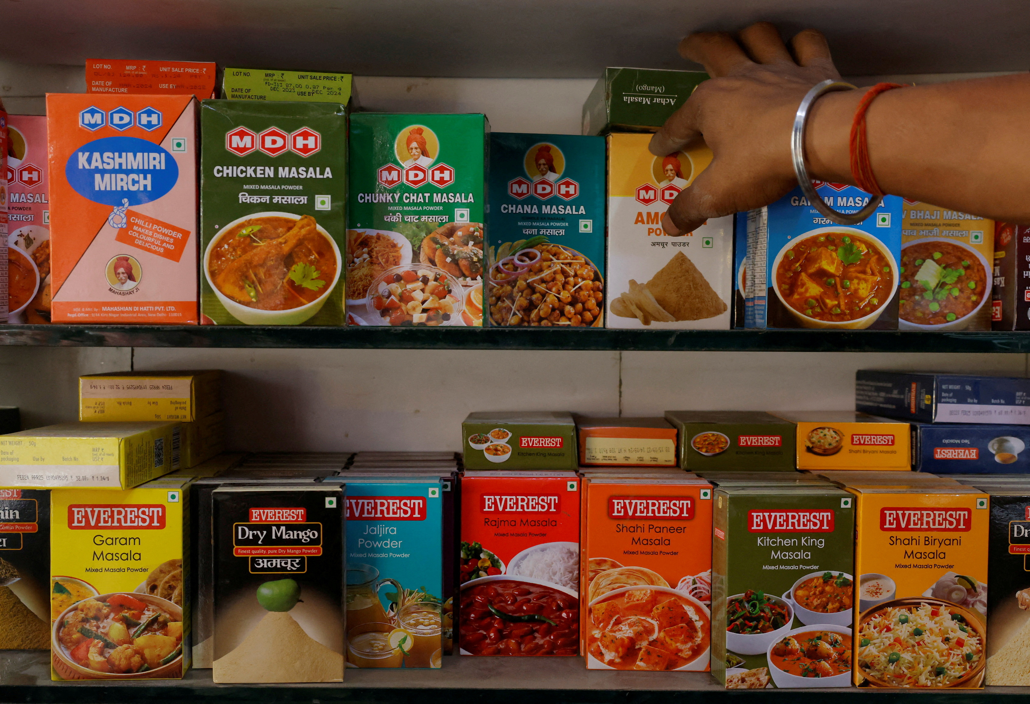FILE PHOTO: A man adjusts the spice boxes of MDH and Everest on the shelf of a shop at a market in New Delhi