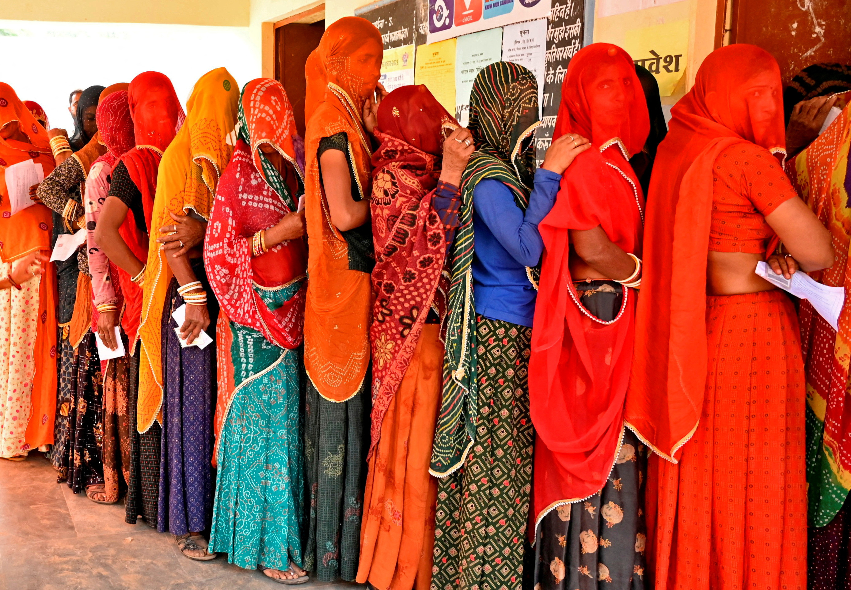 People wait in queues to cast their votes at a polling station in Ajmer