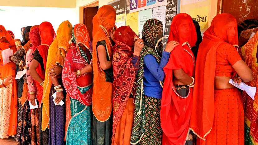 People wait in queues to cast their votes at a polling station in Ajmer