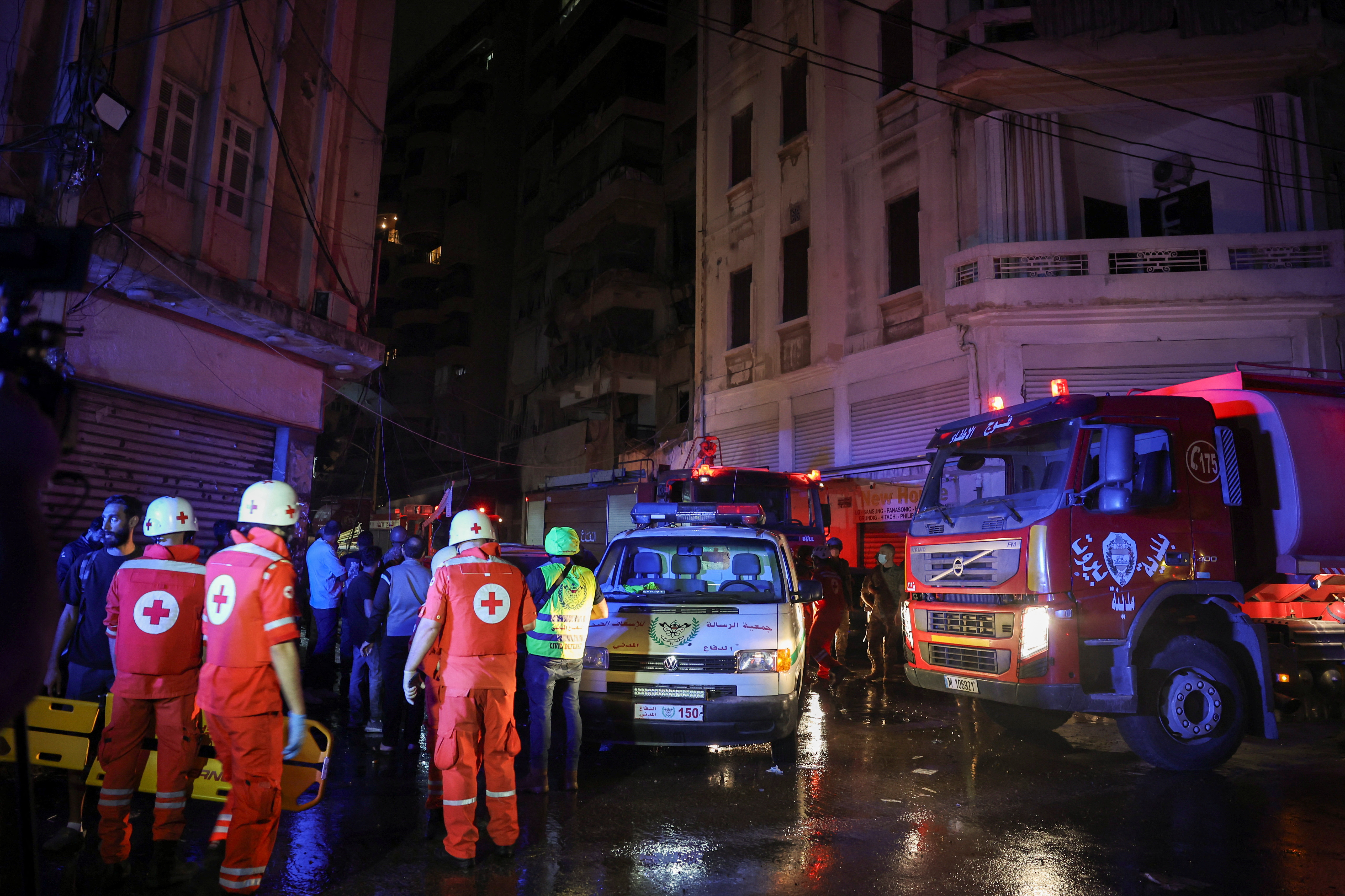 Members of the Red Cross stand near a damaged building at the site of an Israeli air strike, in Beirut