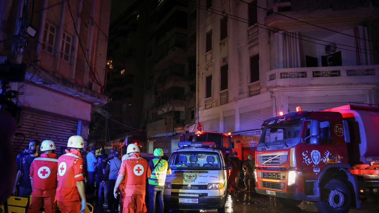 Members of the Red Cross stand near a damaged building at the site of an Israeli air strike, in Beirut