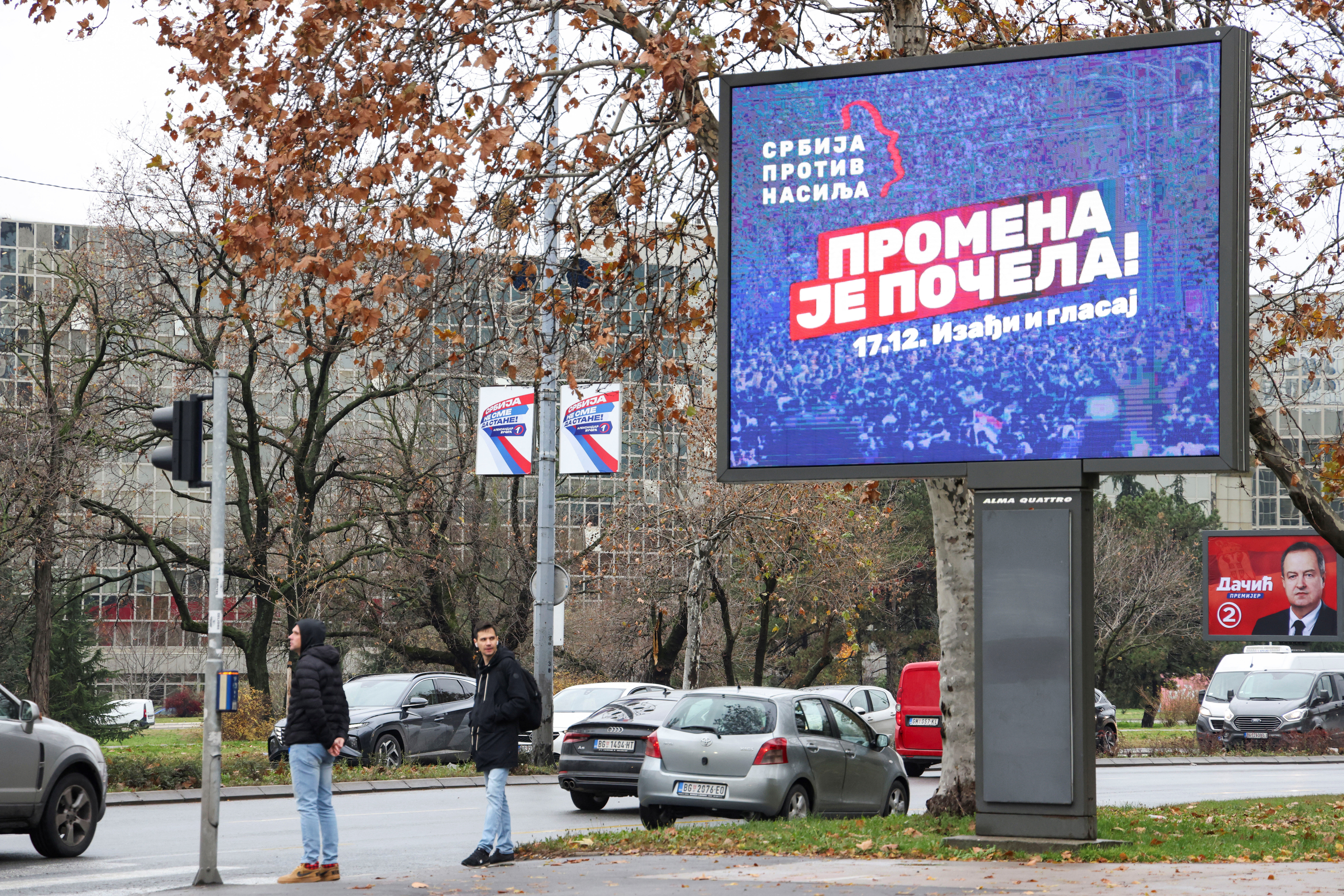 People stand next to a pre-election billboard of opposition coalition 'Serbia Against Violence'  in Belgrade