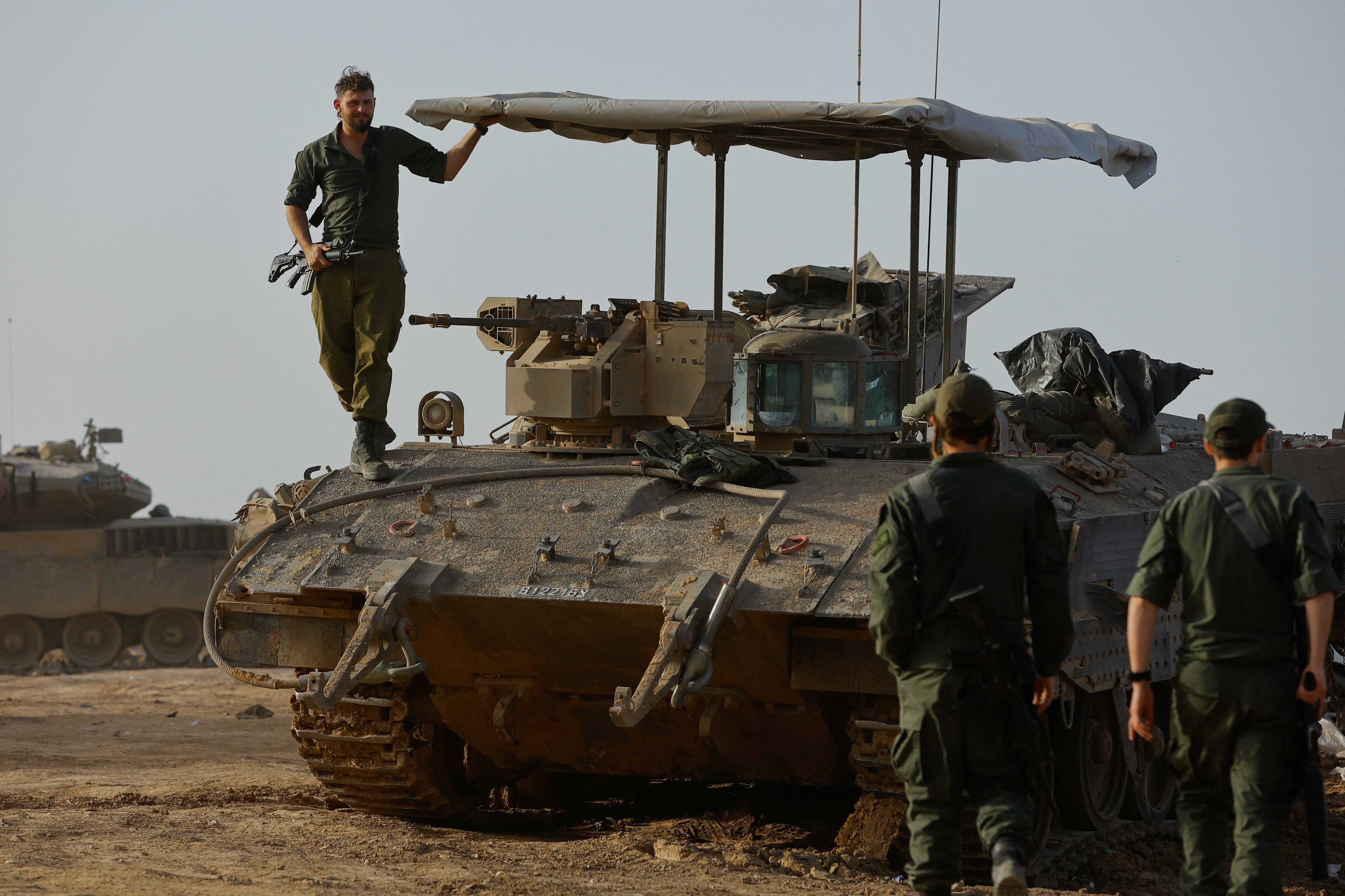 An Israeli soldier stands on an armoured personnel carrier near the Israel-Gaza border during a temporary truce between Hamas and Israel