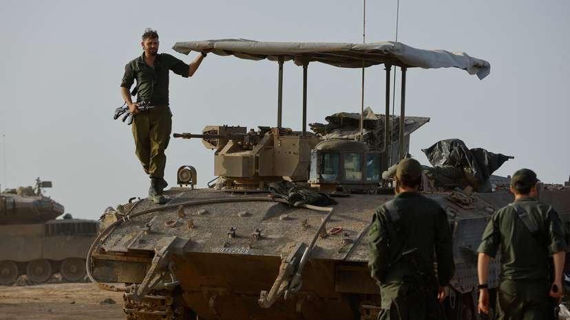 An Israeli soldier stands on an armoured personnel carrier near the Israel-Gaza border during a temporary truce between Hamas and Israel