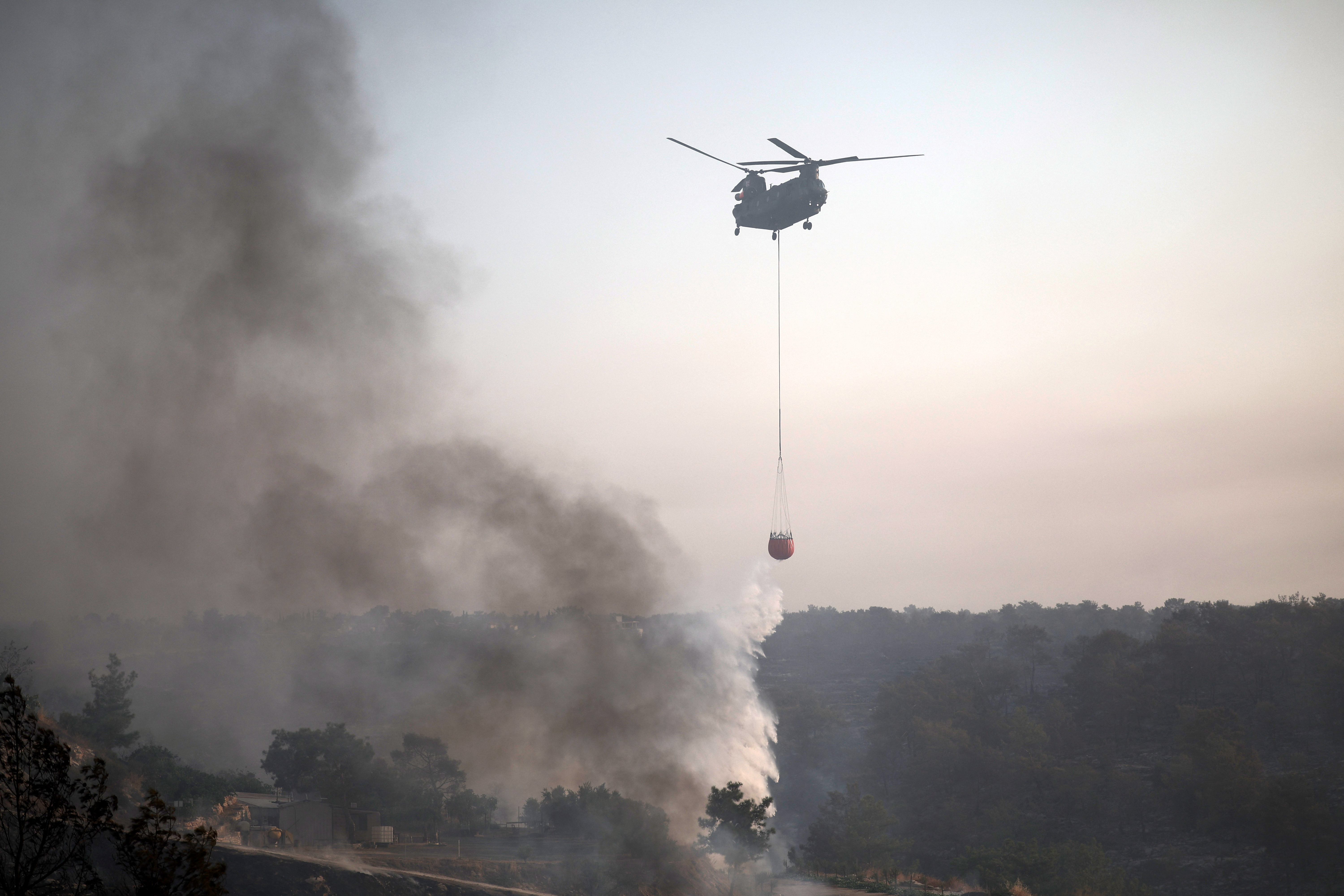 A firefighting helicopter drops water to extinguish fire at the area of Souni near Limassol,
