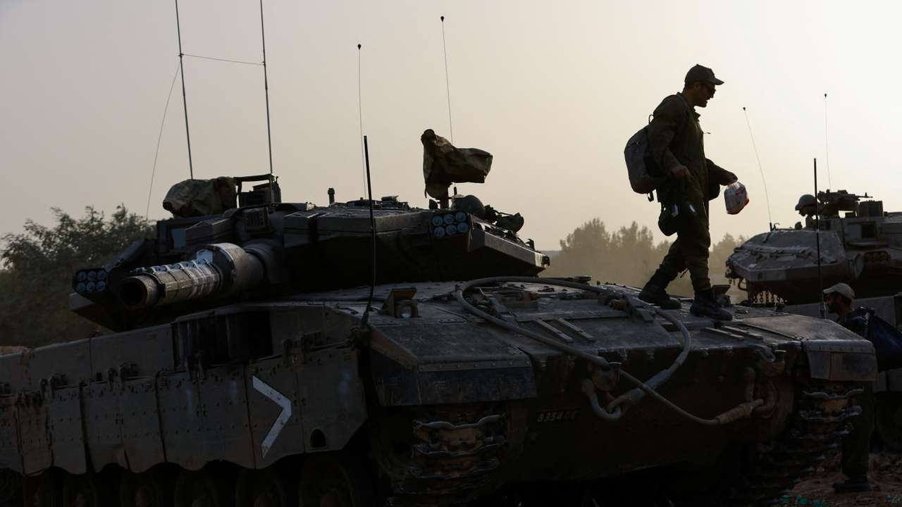 An Israeli soldier walks on a tank near the Israel-Gaza border during a temporary truce between Hamas and Israel