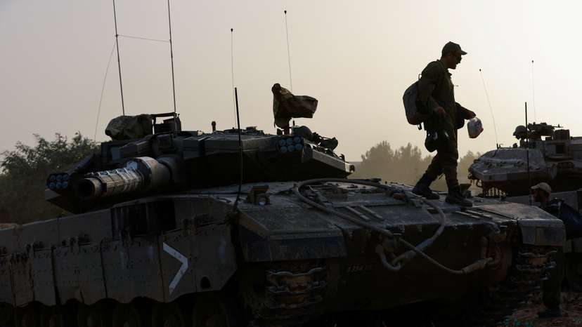 An Israeli soldier walks on a tank near the Israel-Gaza border during a temporary truce between Hamas and Israel