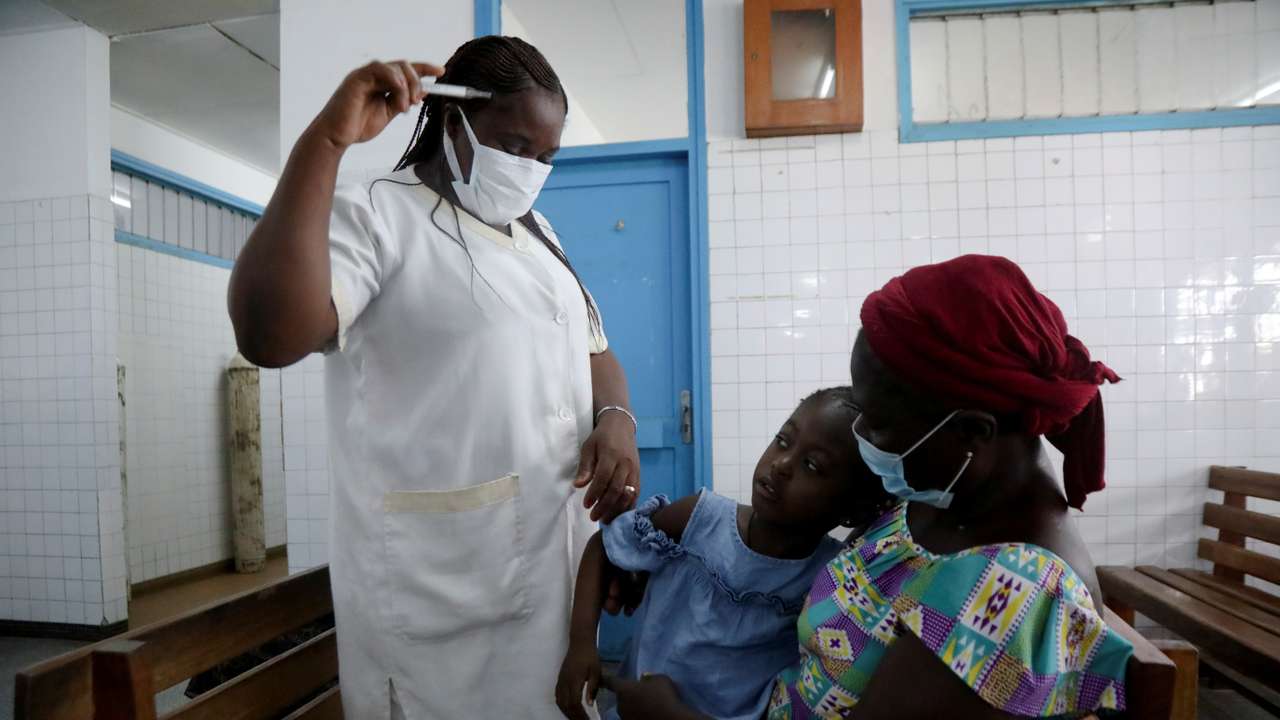 A nurse prepares to take the temperature of a child with malaria at Marcory General Hospital in Abidjan