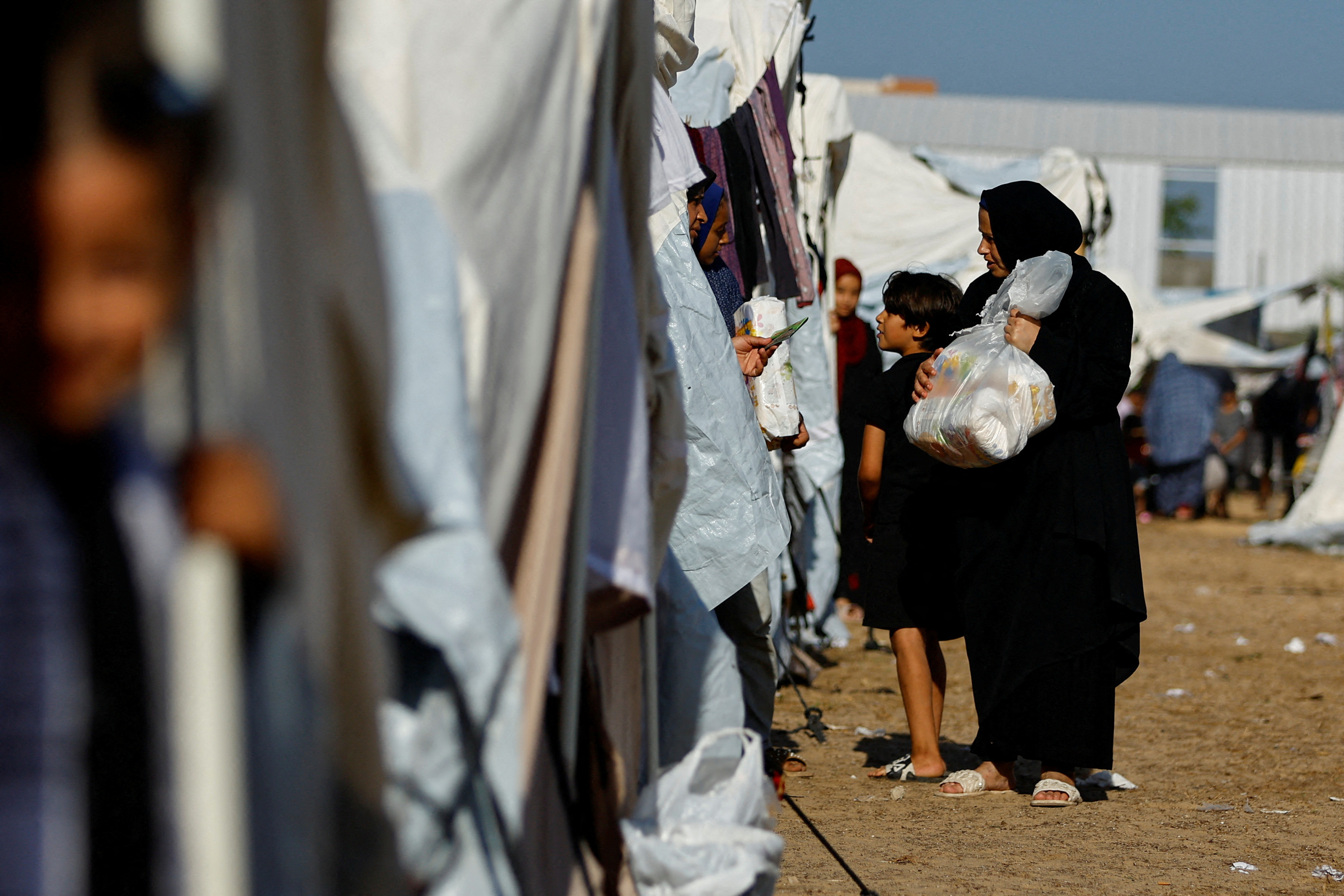FILE PHOTO: Palestinians, who fled their houses amid Israeli strikes, take shelter at a tent camp at a United Nations-run centre, in Khan Younis
