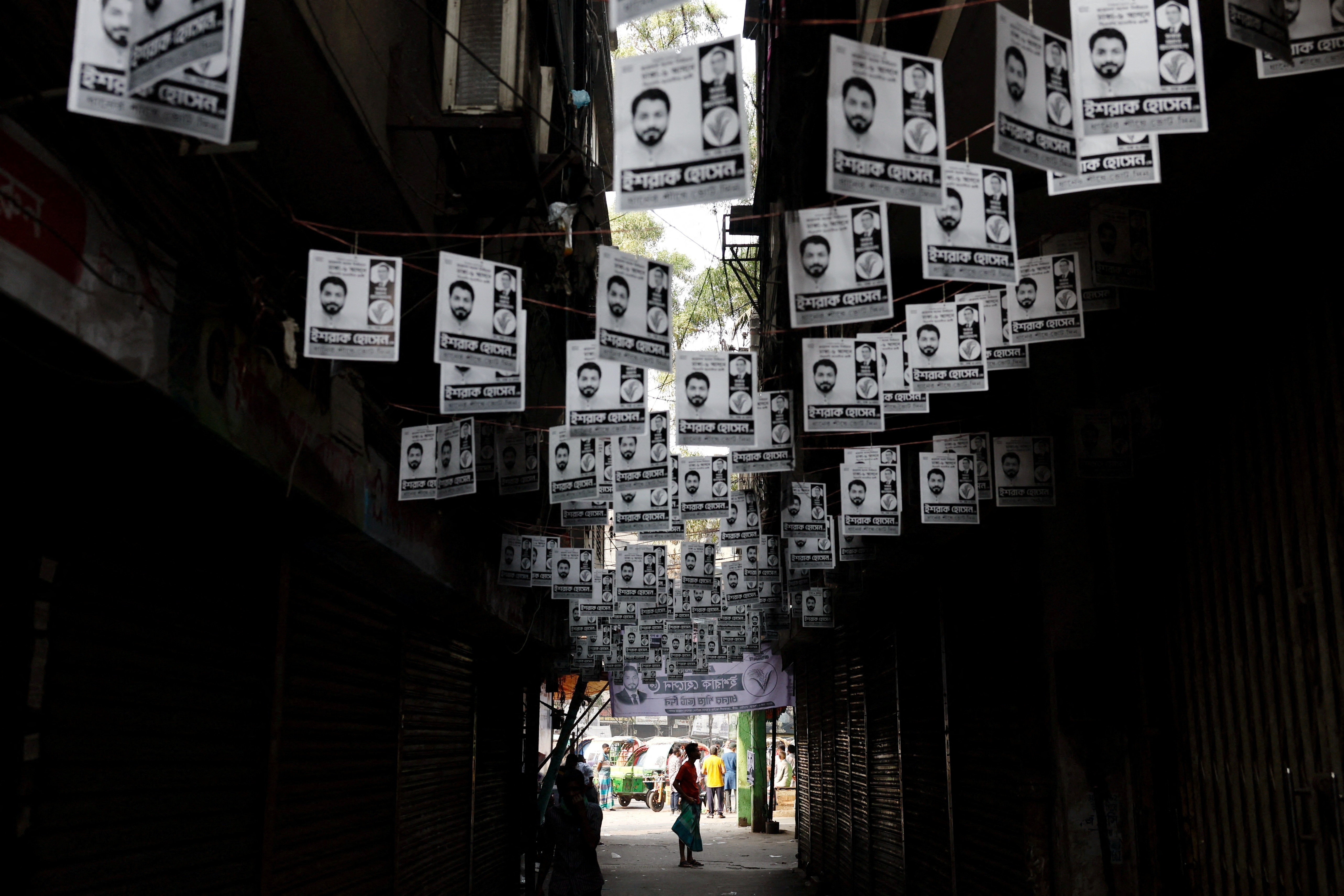 Election campaign posters hang over a street a day ahead of the national election in Dhaka