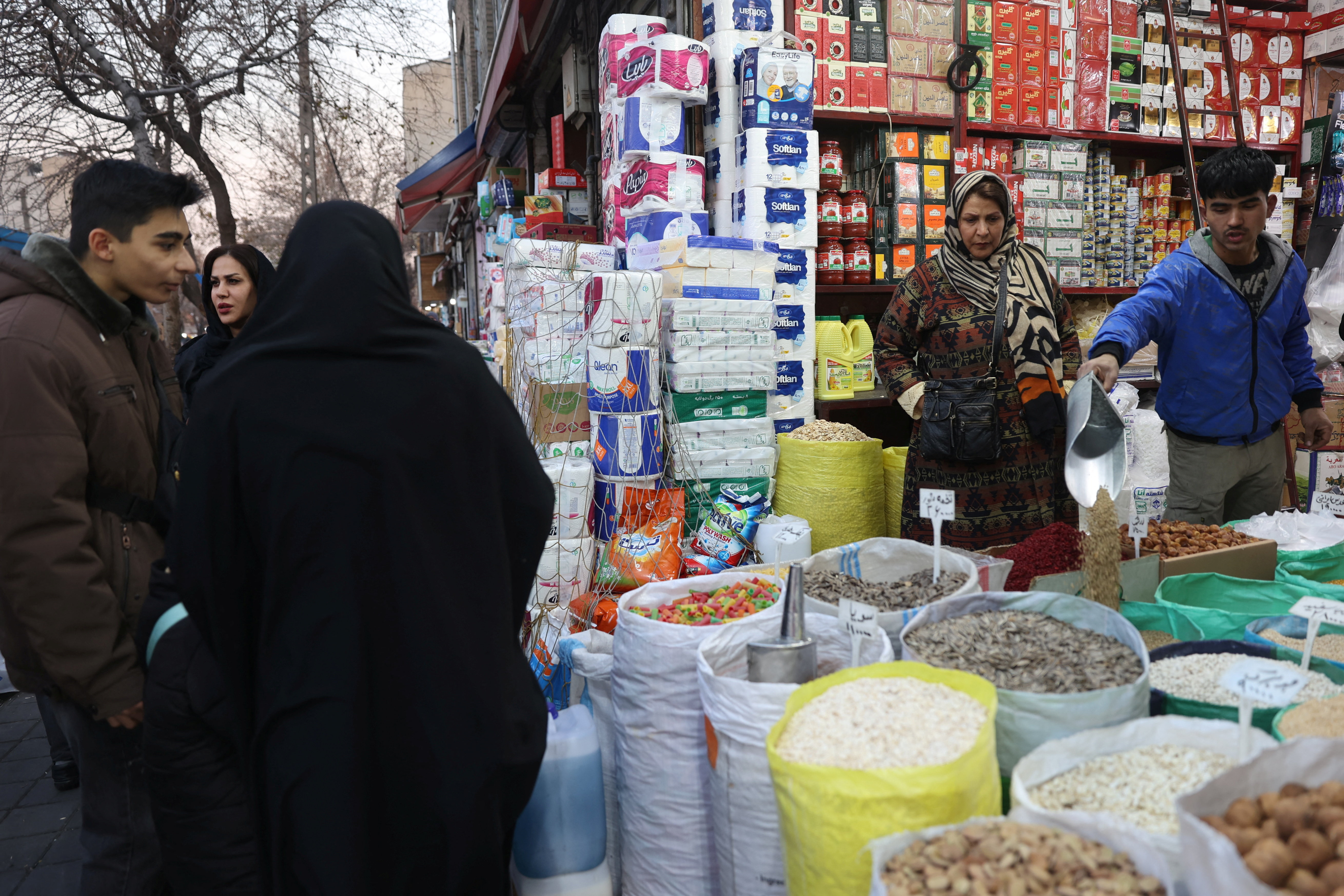 An Iranian woman shops in a local market as protests erupt over the collapse of the currency's value in Tehran