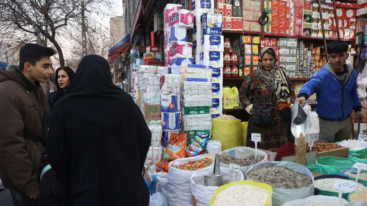 An Iranian woman shops in a local market as protests erupt over the collapse of the currency's value in Tehran