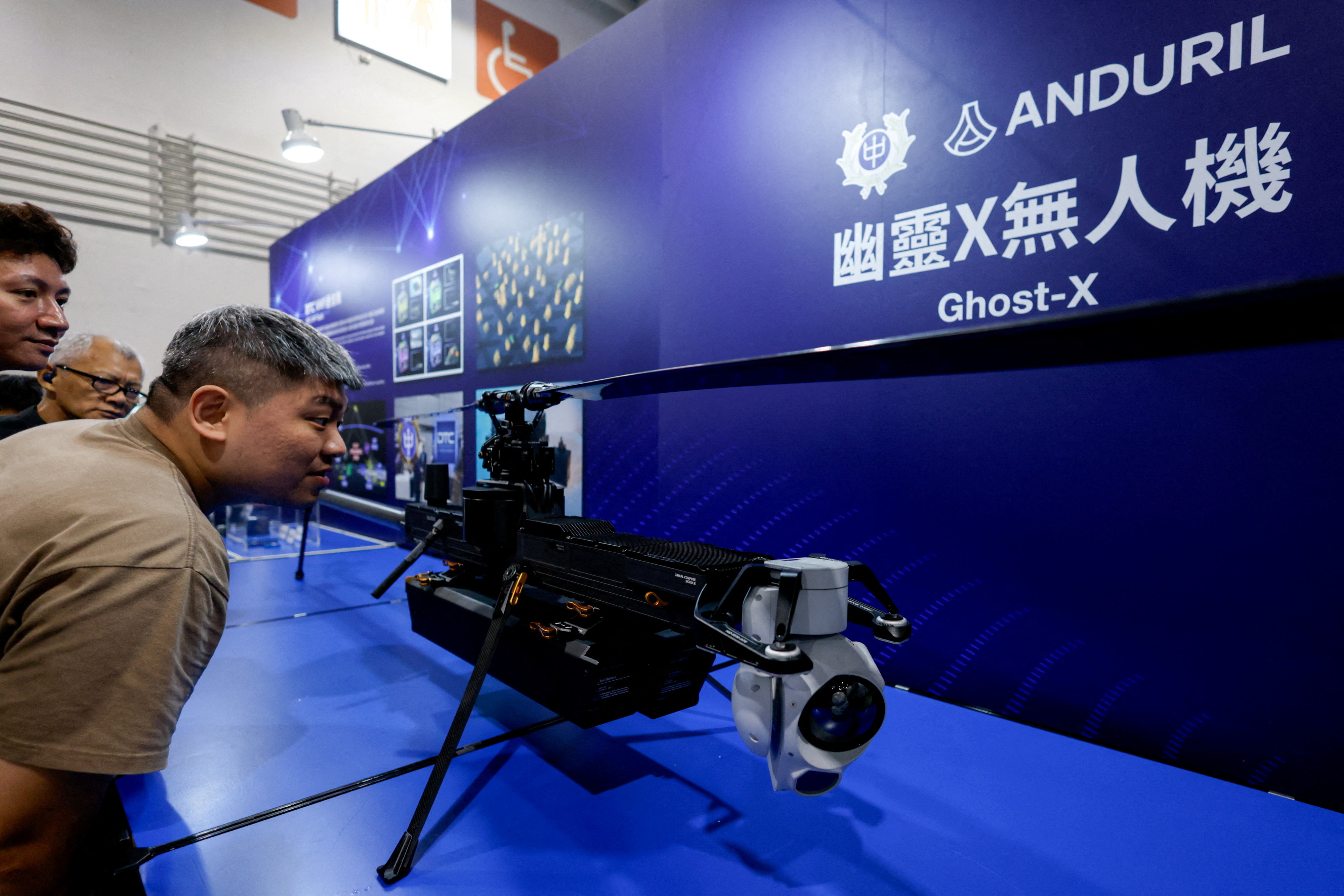 FILE PHOTO: Visitors look at the Ghost-X unmanned aerial vehicle developed by U.S. company Anduril
