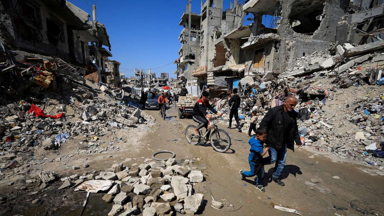 Palestinians pass by the rubble of destroyed houses, in Gaza City