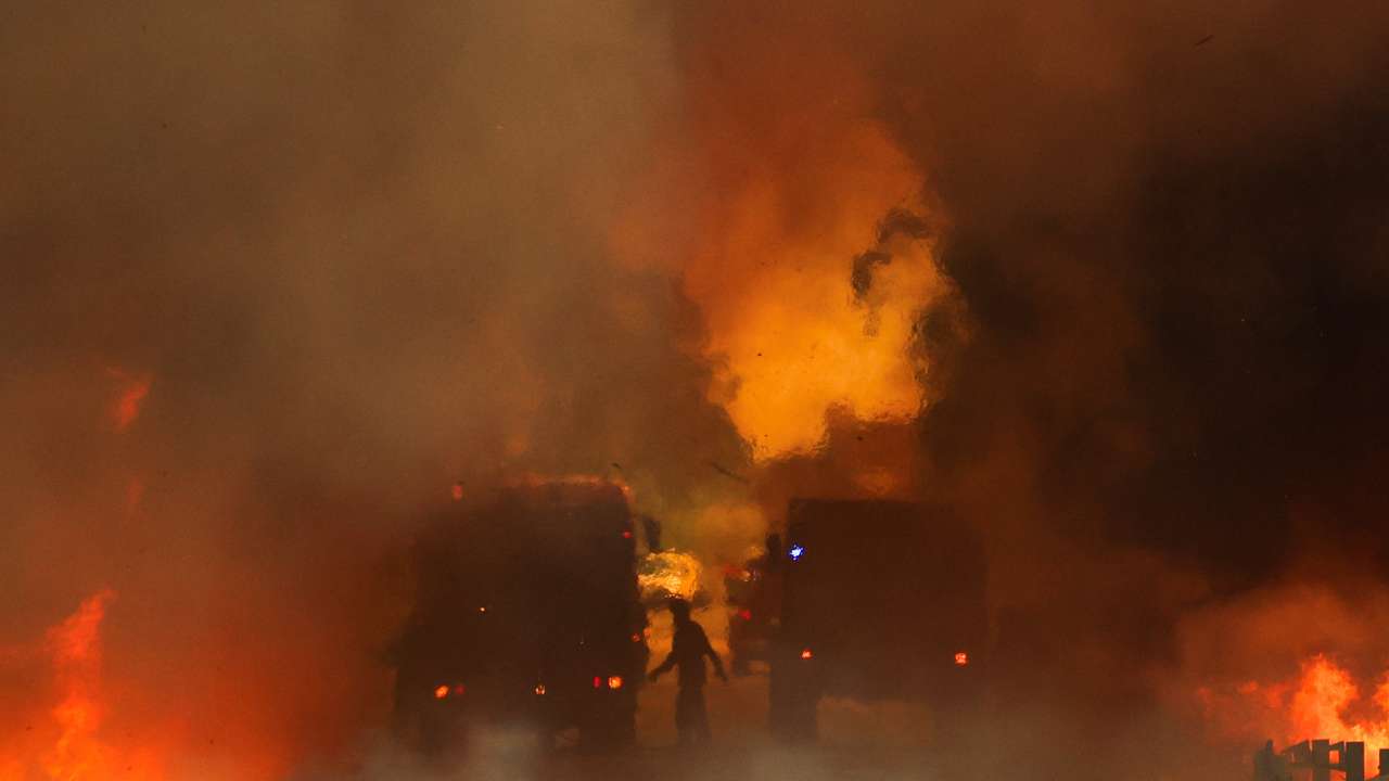 Firefighters try to extinguish a wildfire on a road in Junqueiro, Agueda