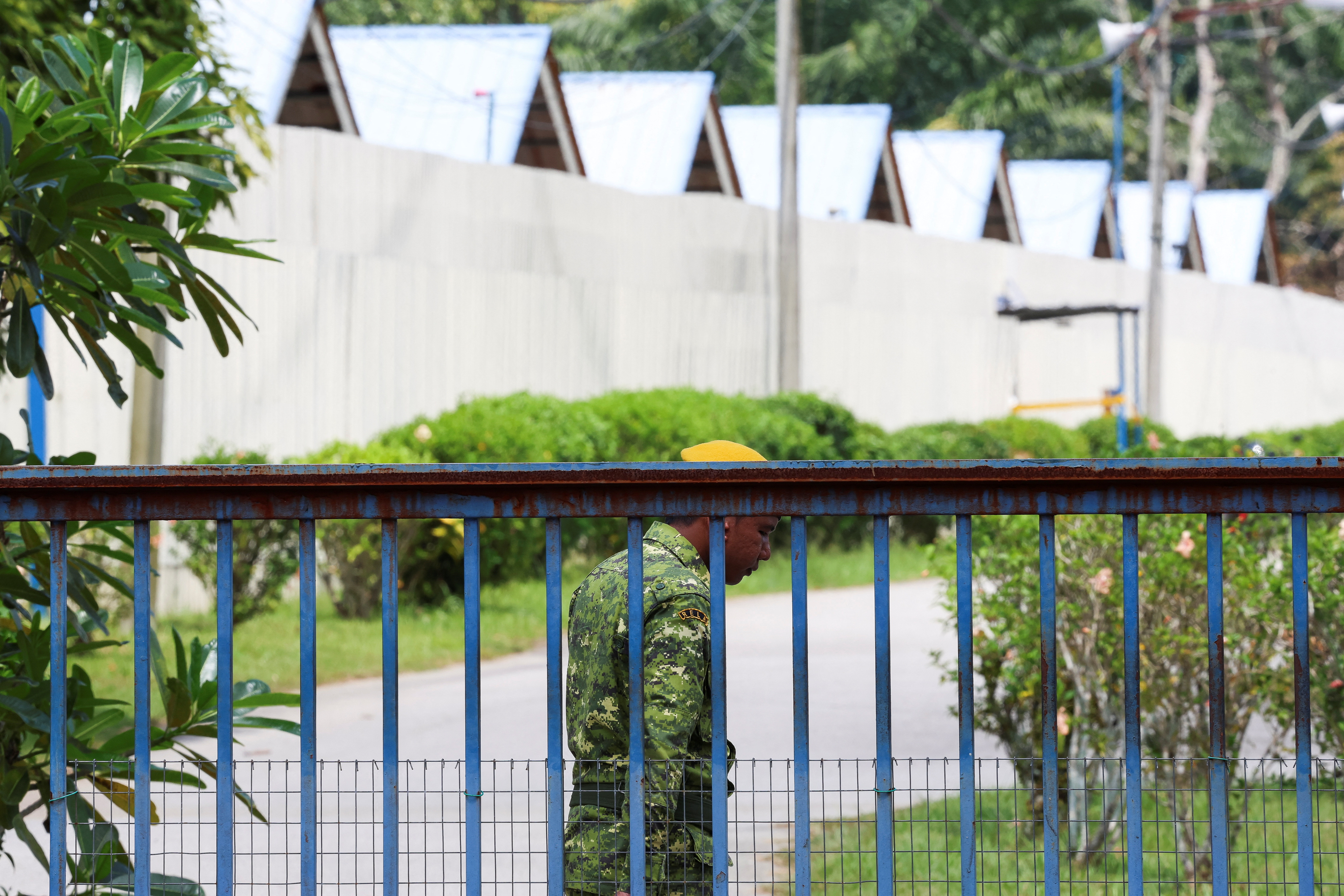 A security guard is stationed at the entrance of an immigration detention centre where more than 100 Myanmar migrants, including Rohingya refugees, escaped, at Bidor