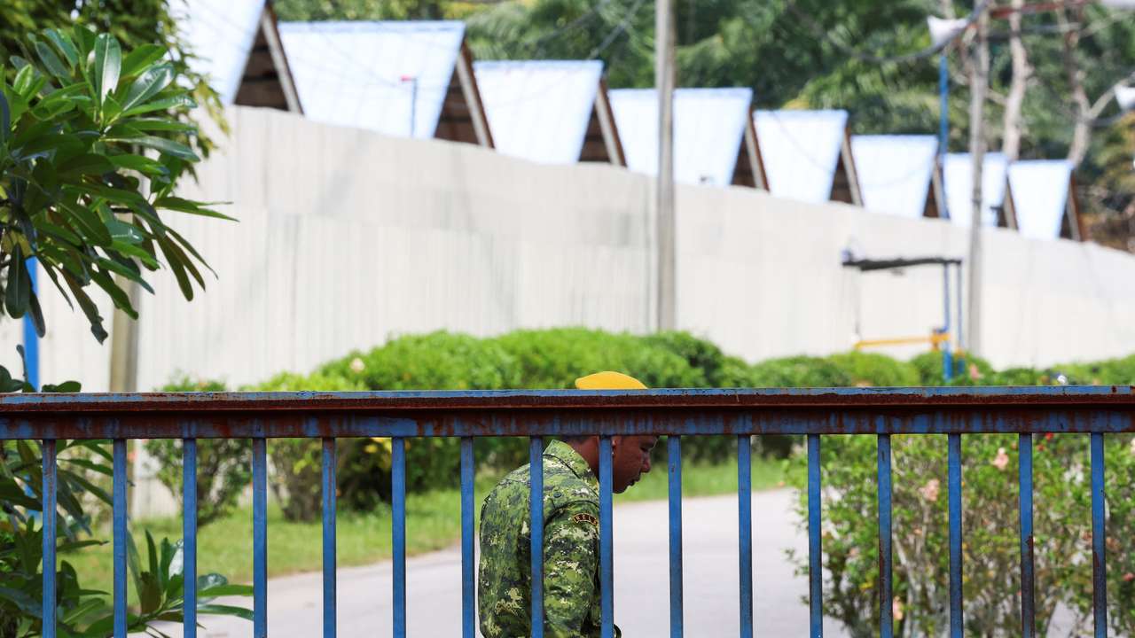 A security guard is stationed at the entrance of an immigration detention centre where more than 100 Myanmar migrants, including Rohingya refugees, escaped, at Bidor