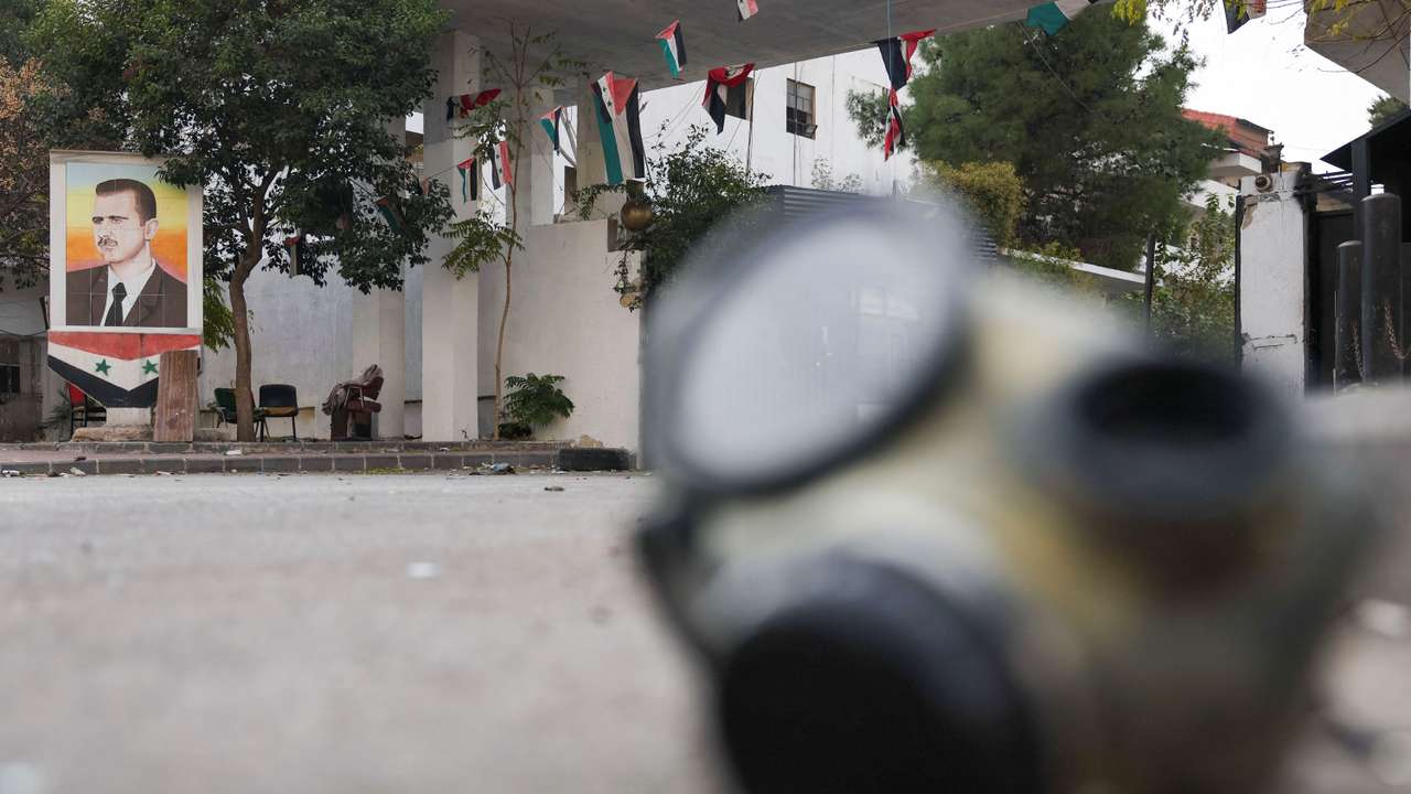 A picture of Syria's Bashar al-Assad hangs behind a mask outside the prison "Branch 215"which was operated by Syrian Military Intelligence in Damascus
