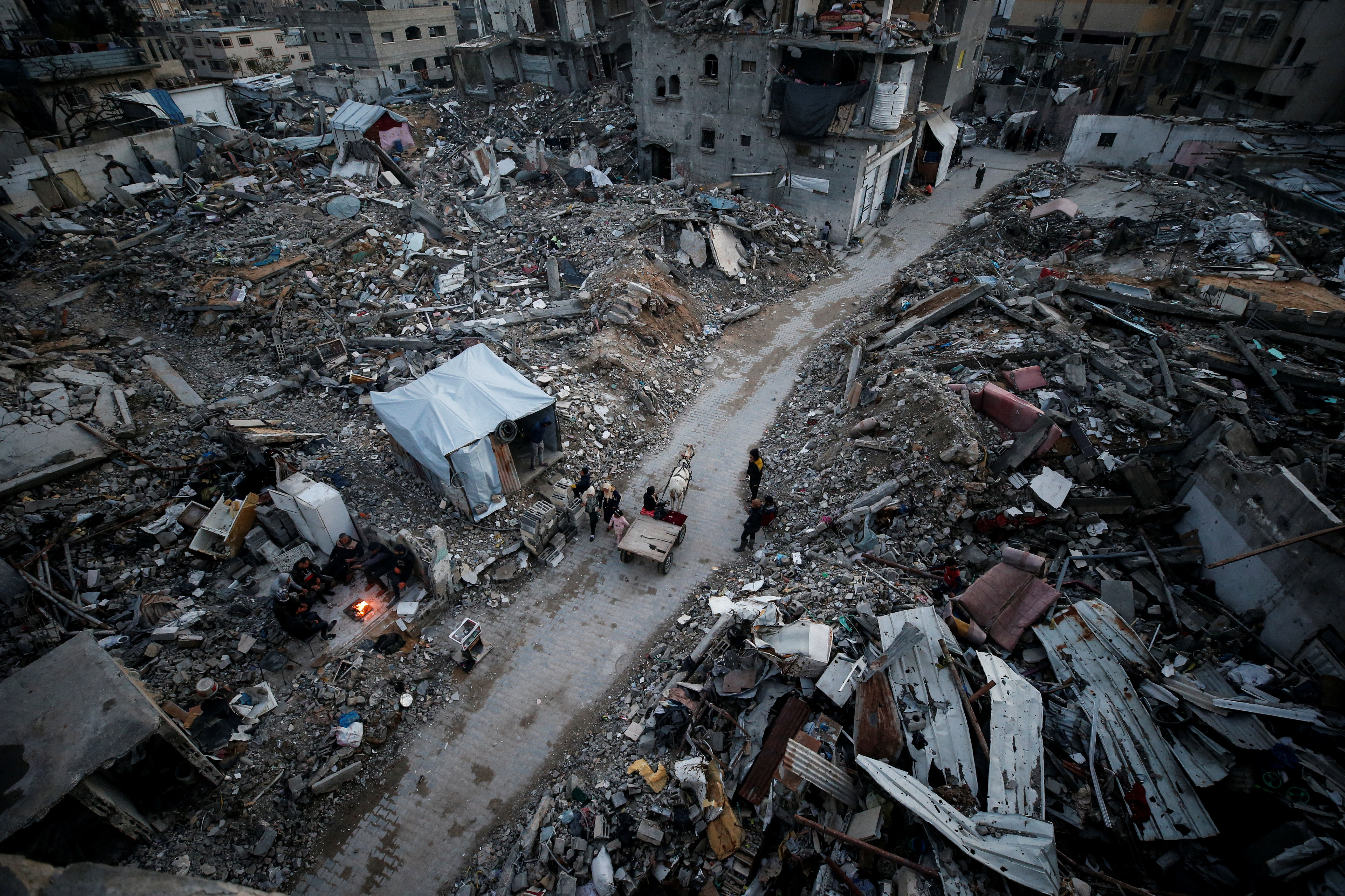 Palestinians walk past the rubble of destroyed houses, at Jabalia refugee camp