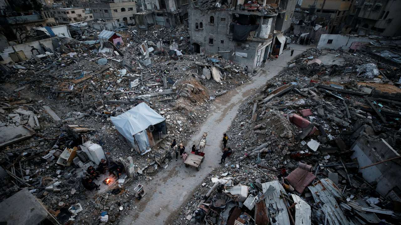 Palestinians walk past the rubble of destroyed houses, at Jabalia refugee camp