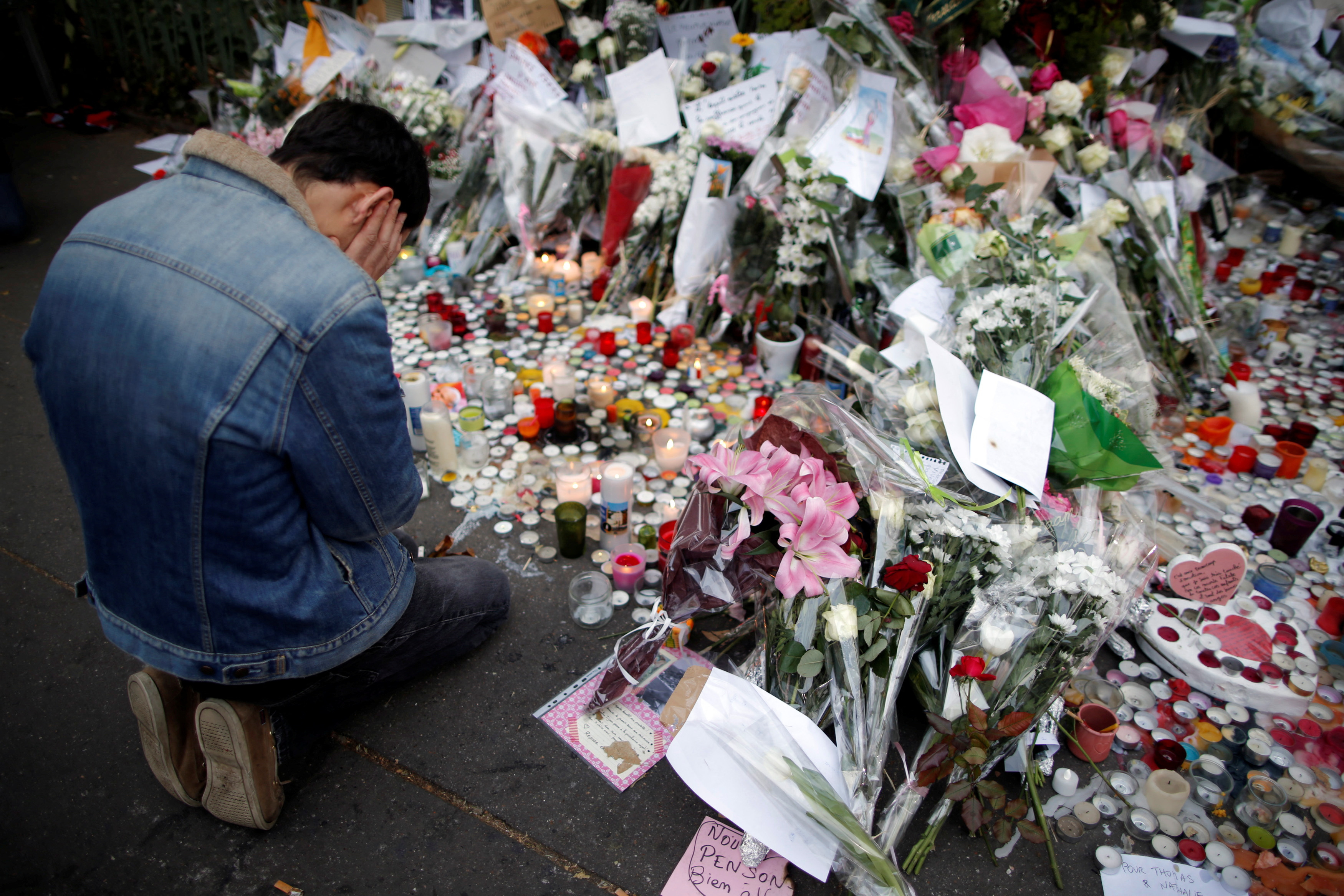 FILE PHOTO: A man kneels as he pays tribute to victims near the site of the attack at the Bataclan concert hall in Paris