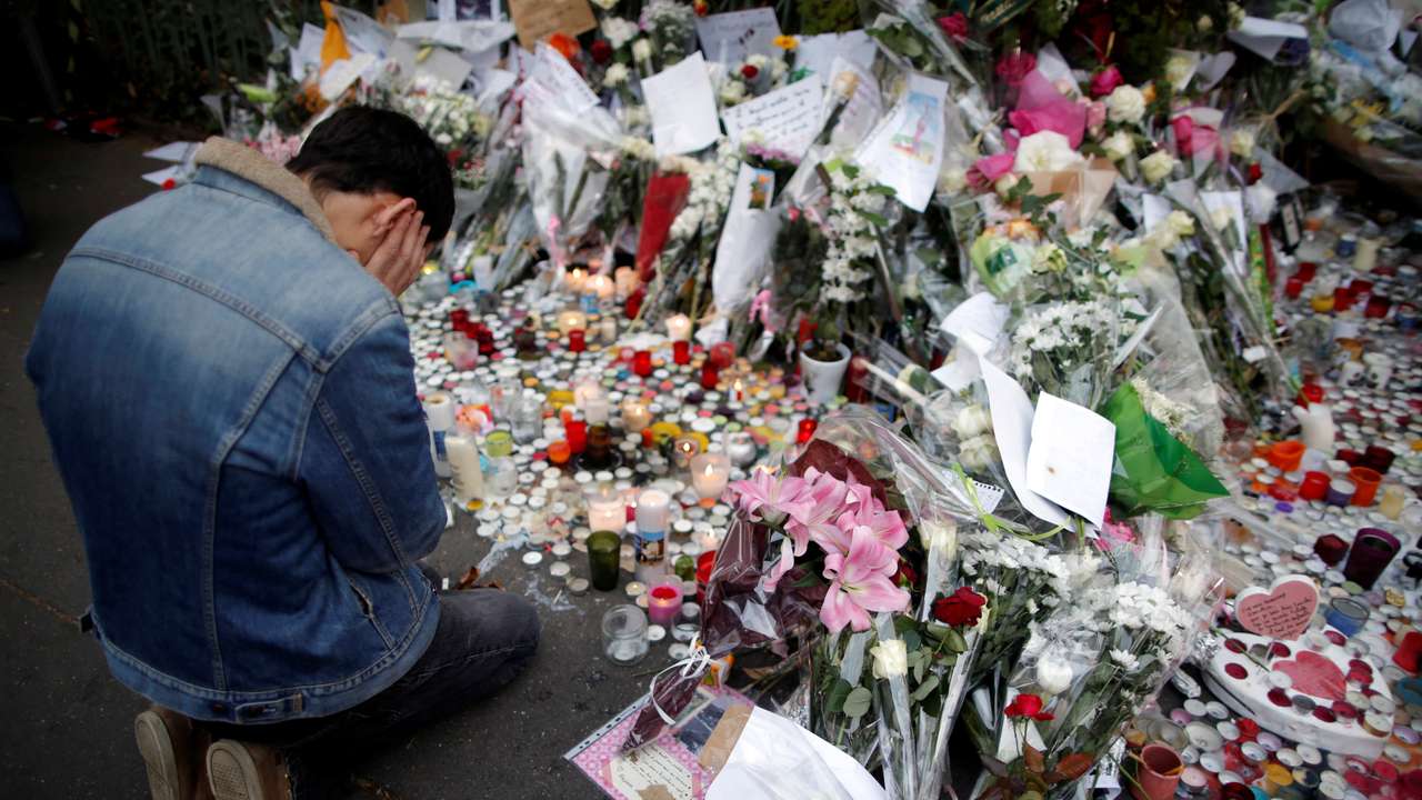 FILE PHOTO: A man kneels as he pays tribute to victims near the site of the attack at the Bataclan concert hall in Paris