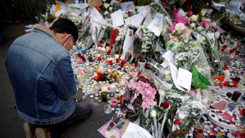 FILE PHOTO: A man kneels as he pays tribute to victims near the site of the attack at the Bataclan concert hall in Paris