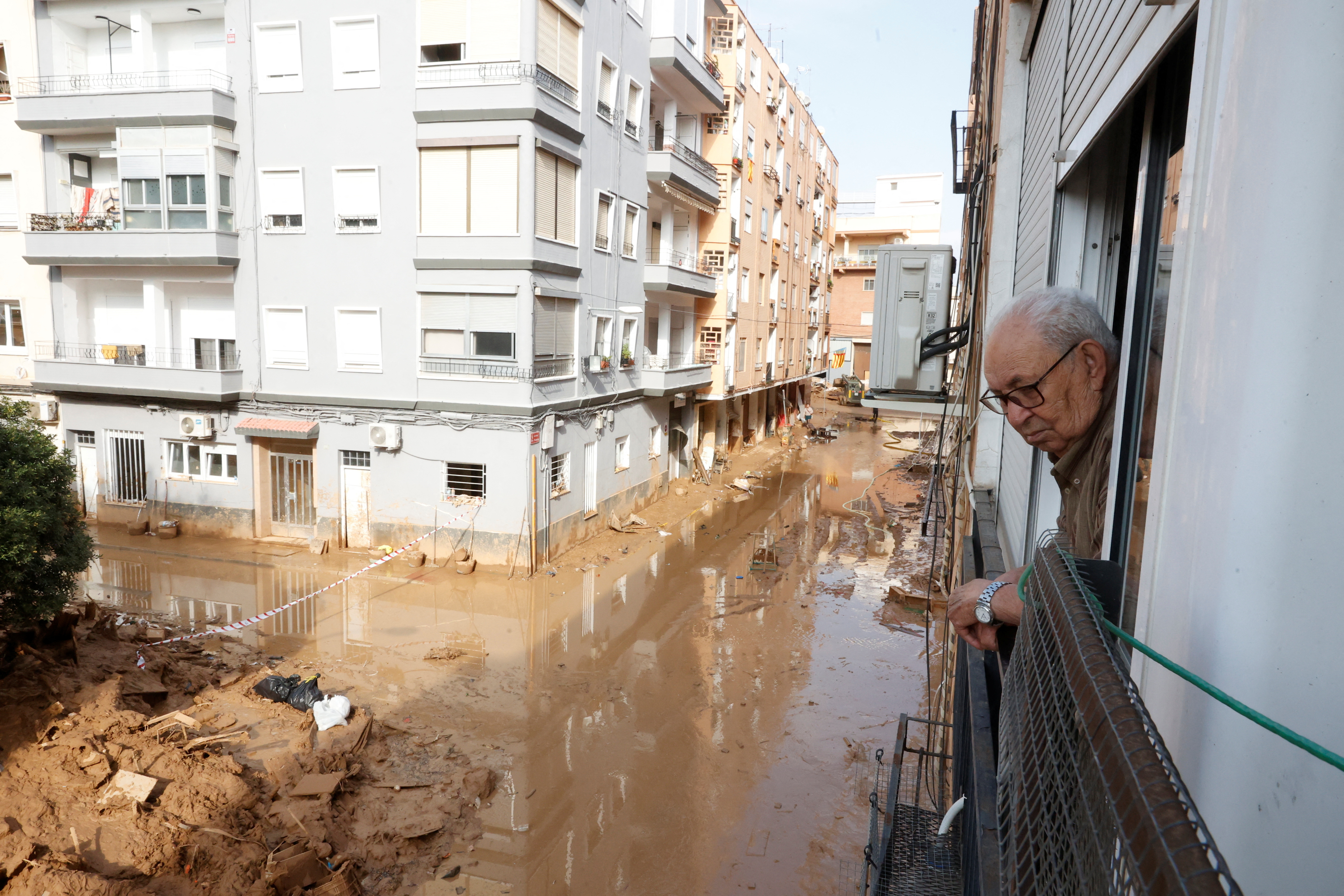 Cristobal Martinez, 87, looks out of his window at the muddy streets in Paiporta