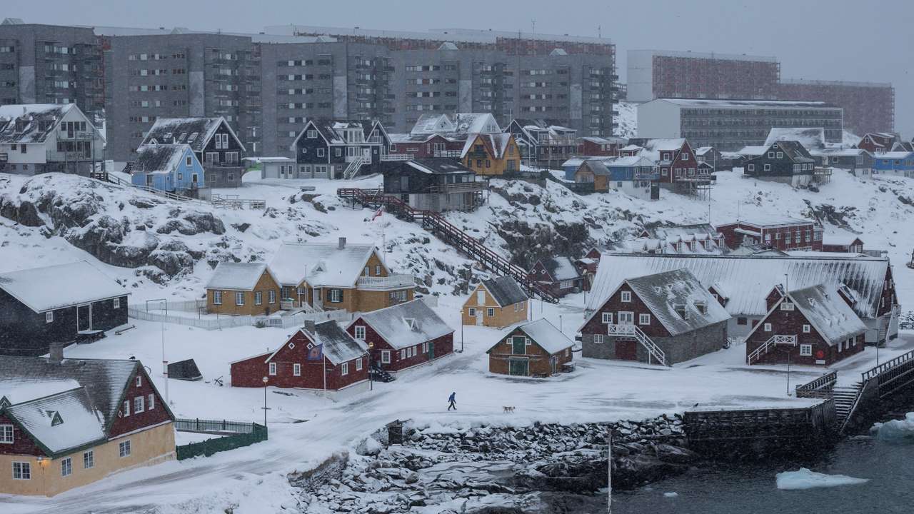 A man walks a dog at Nuuk's old harbour