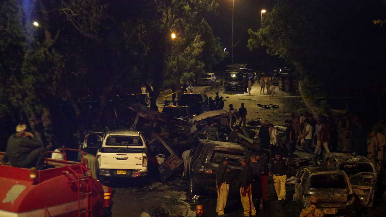 Police officers and paramilitary soldiers gather near the wreckage of vehicles after an explosion near Jinnah International Airport in Karachi