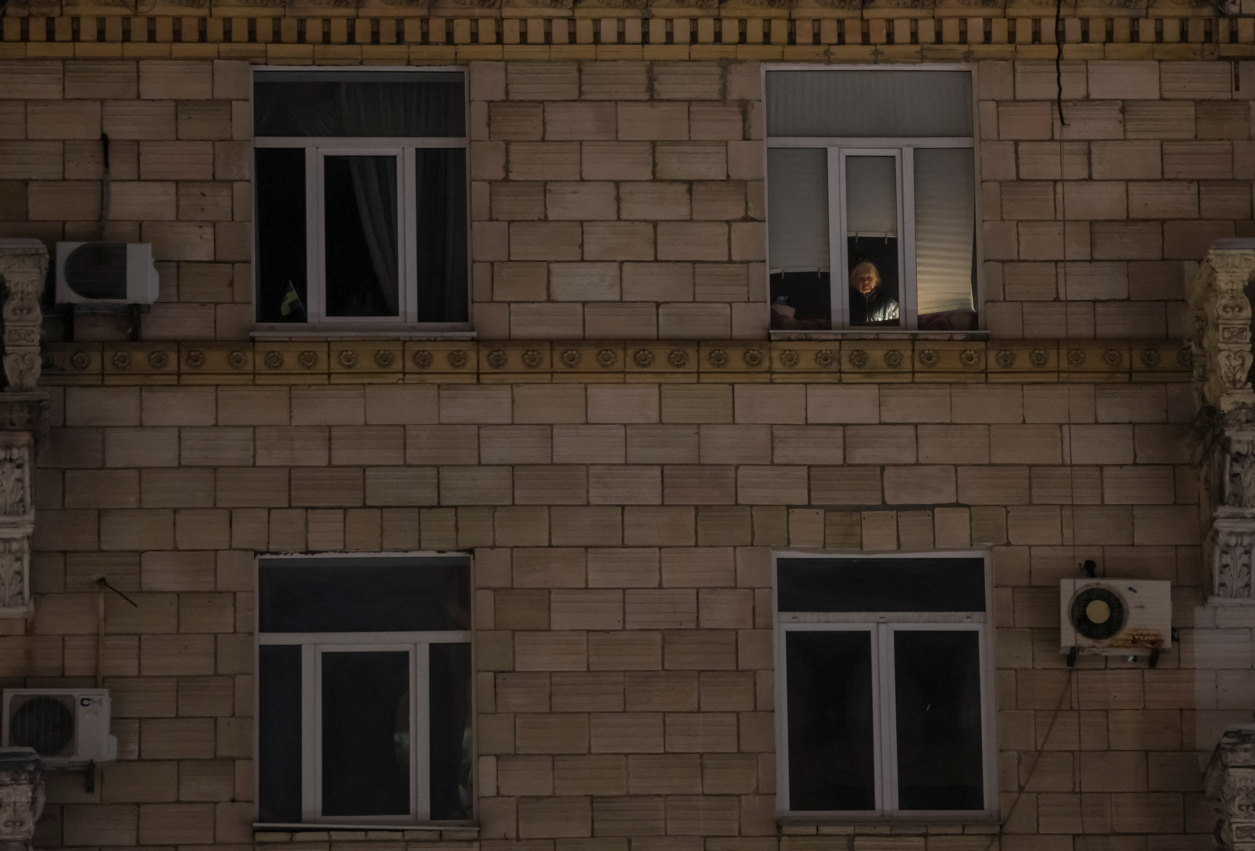 A resident looks out the window during a power blackout in Kyiv
