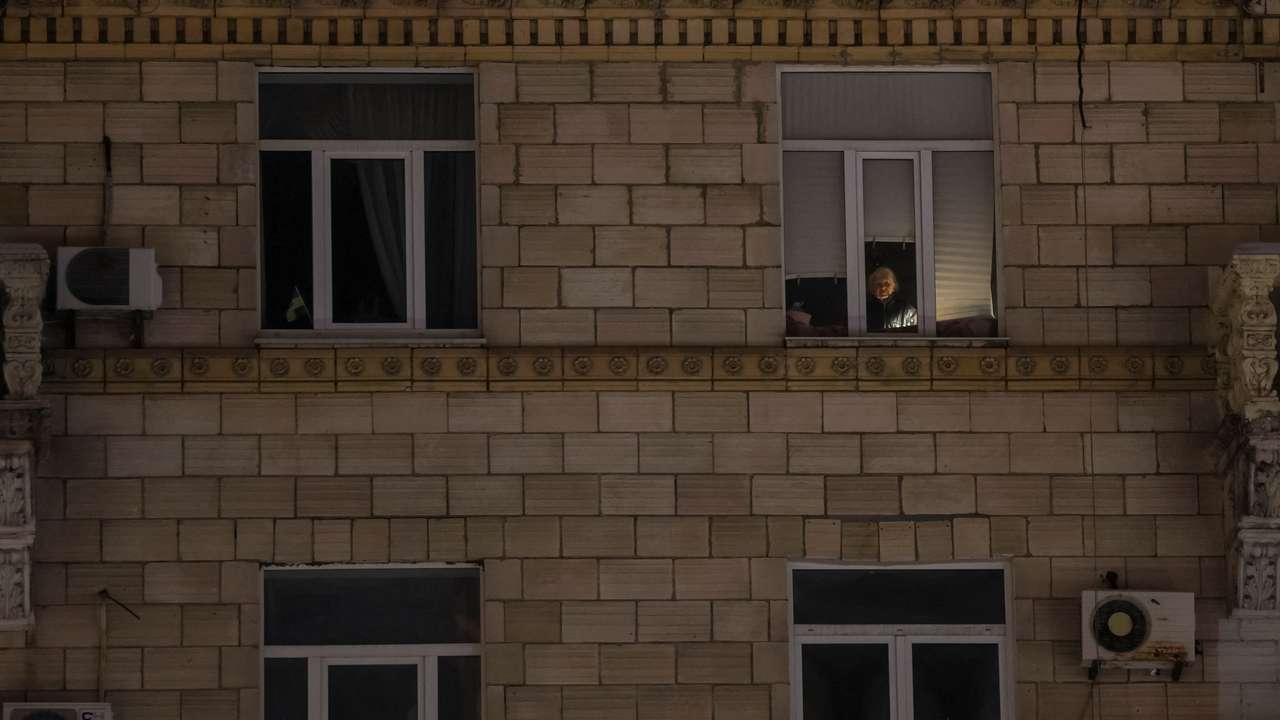 A resident looks out the window during a power blackout in Kyiv