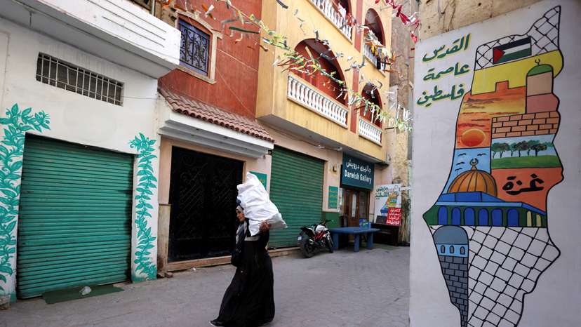 An Egyptian woman carries a food bag and walks next to painting of a map in old Cairo