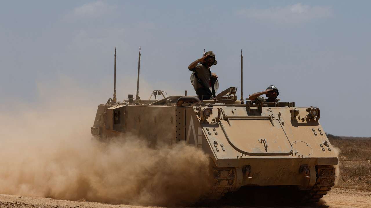 Israeli soldiers salute on a military vehicle as they manoeuvre, near the Israel-Gaza border
