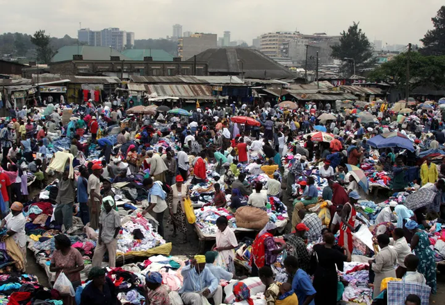 Sellers offering second-hand clothes wait for customers in a market in Uganda