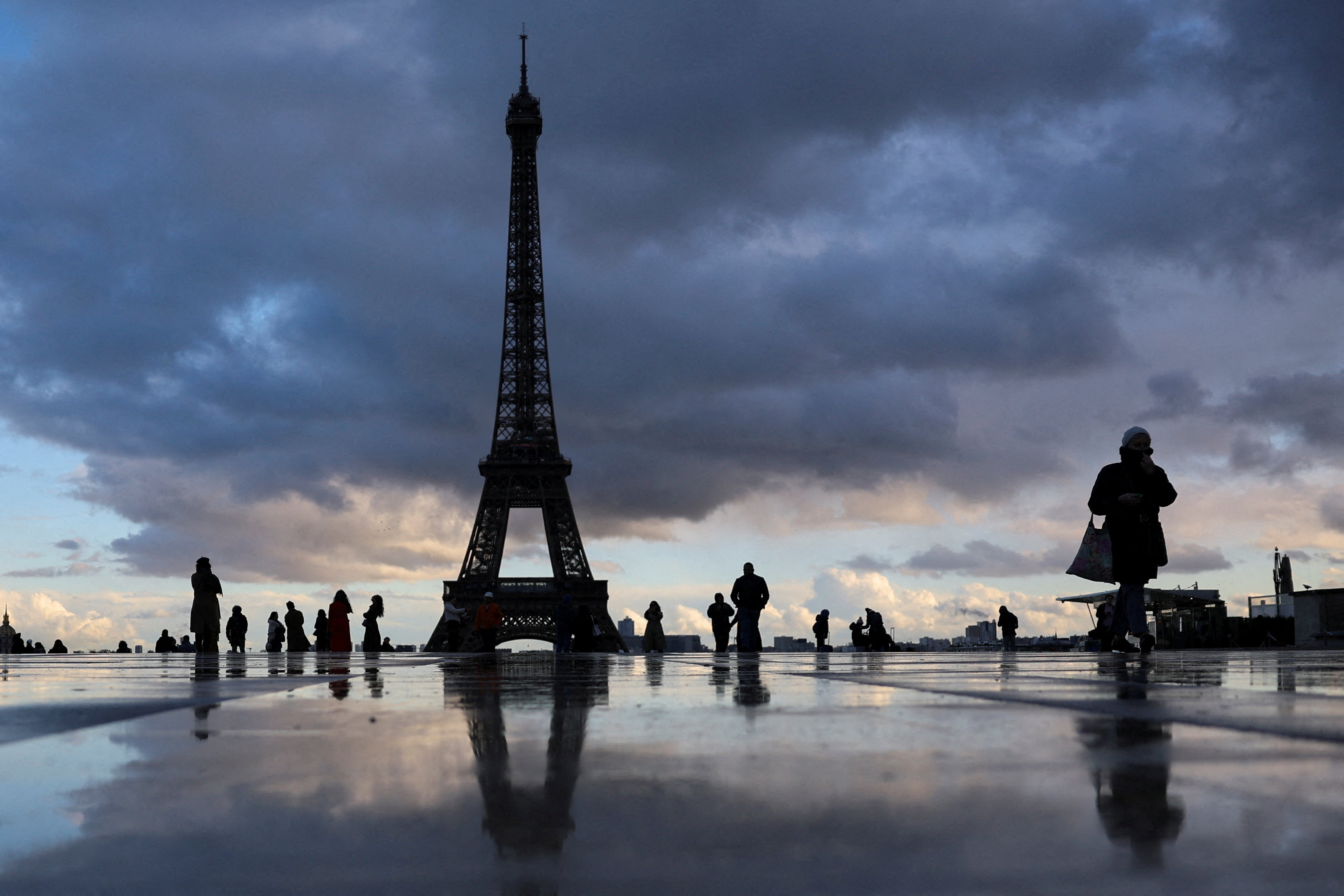 People stand at the Trocadero square near the Eiffel Tower in Paris