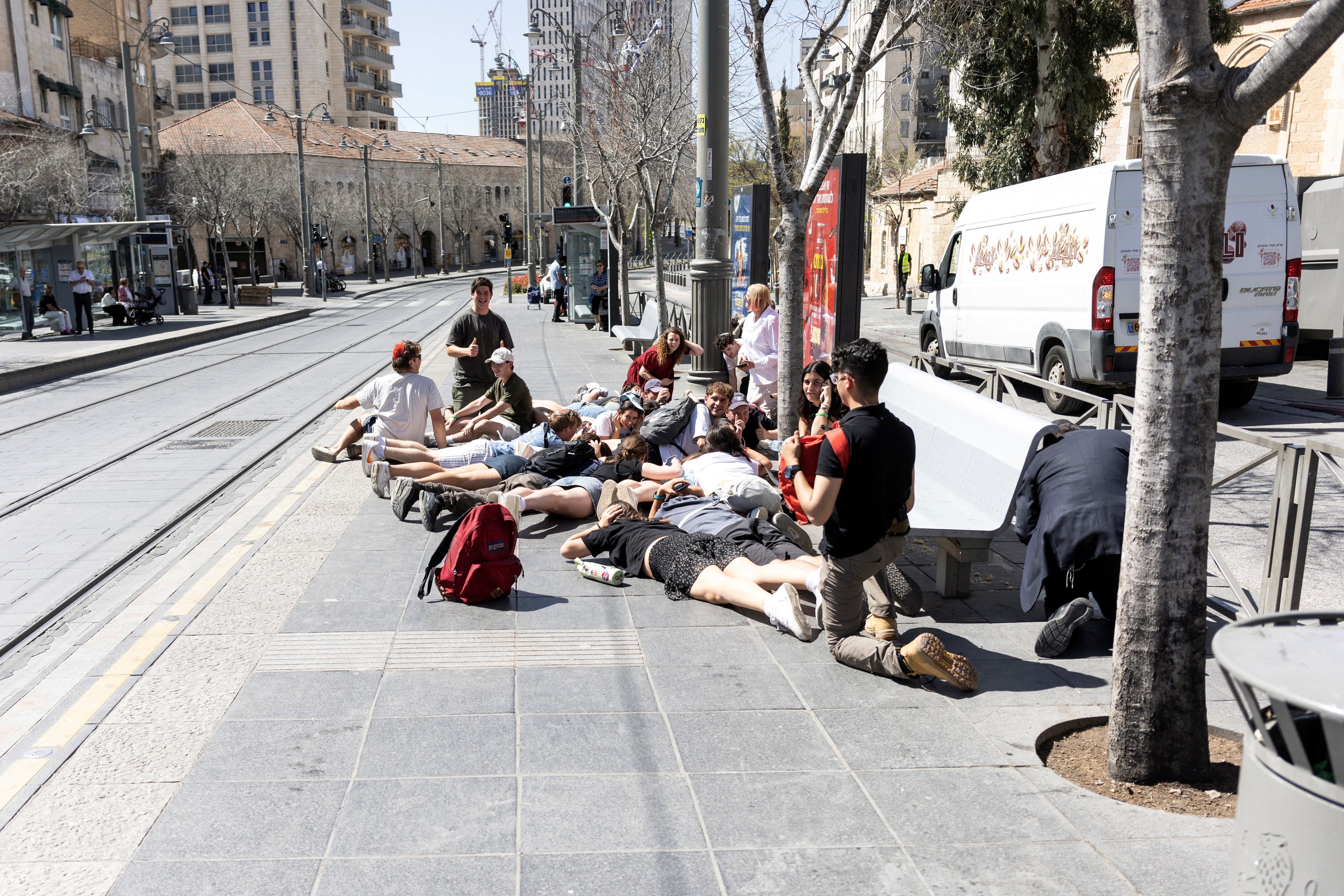 People take cover as the sound of sirens indicate a missile attack from Yemen, in central Jerusalem