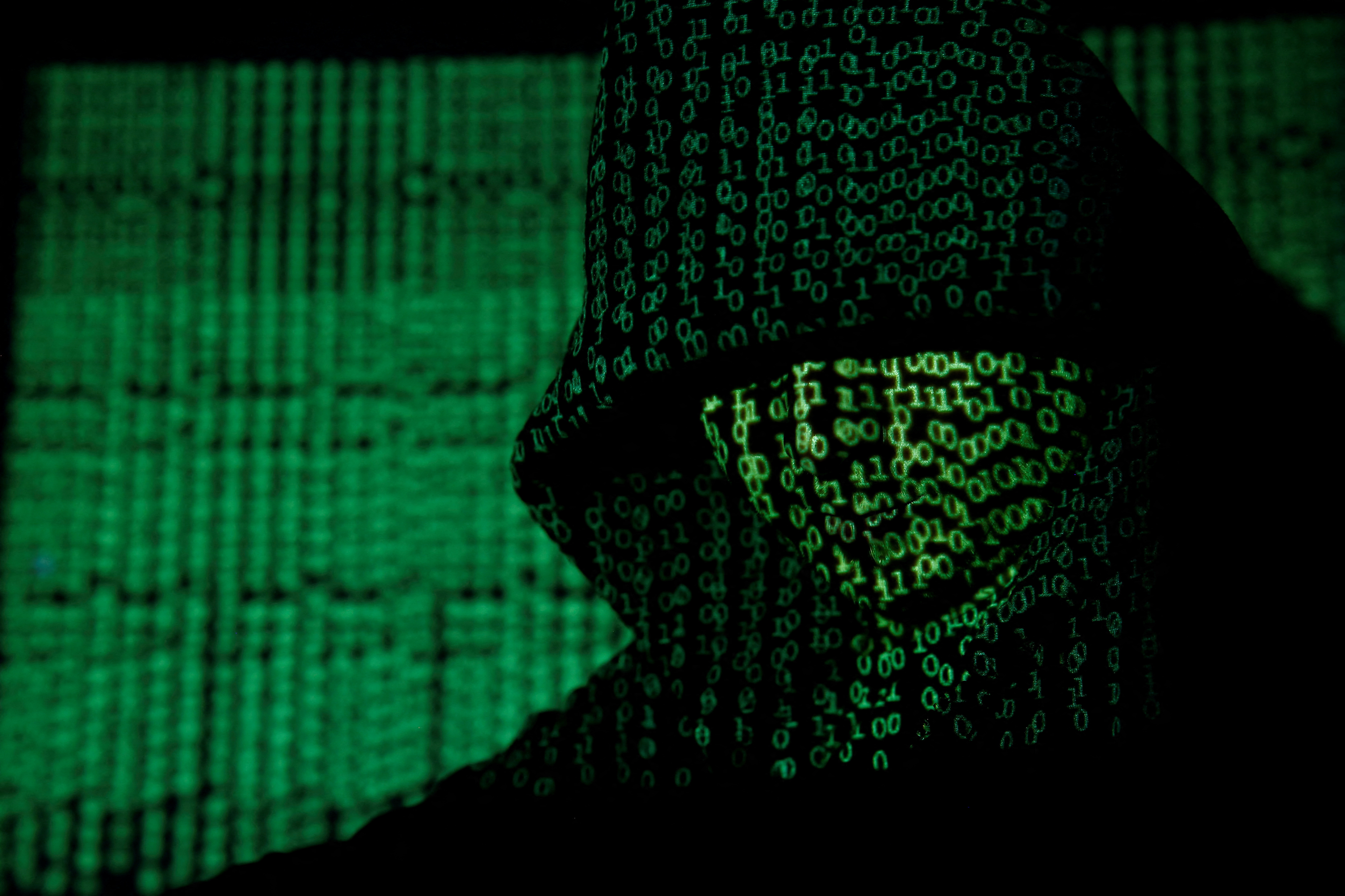 FILE PHOTO: Projection of cyber code on hooded man is pictured in this illustration picture
