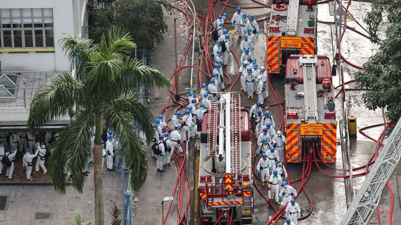 Police officers wearing protective suits walk near the site of a fire-damaged residential block at Wang Fuk Court housing complex in Tai Po, Hong Kong