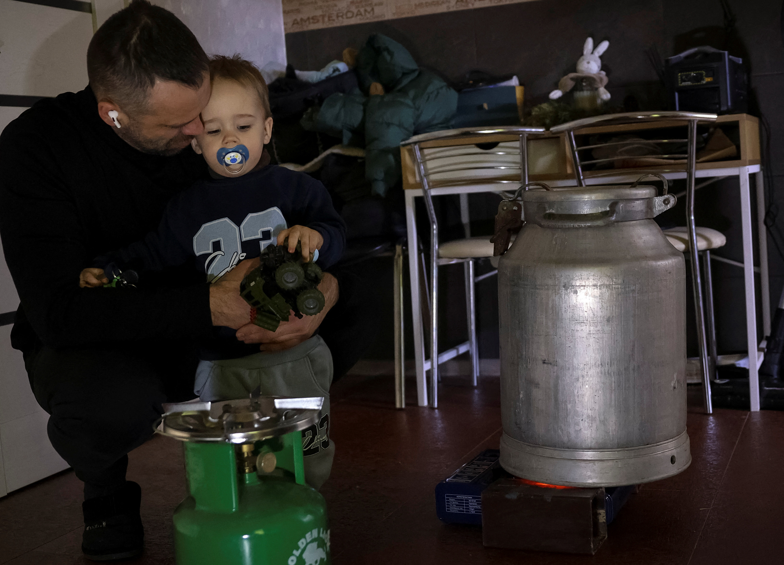 Residents heats a metal churn with water trying to warm his apartment  during a power blackout after critical civil infrastructure was hit by recent a Russian missile and drone attacks, in Kyiv
