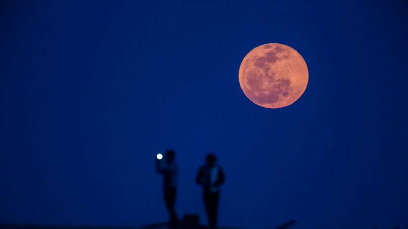 A man takes a picture during moon rise in a suburb of Shanghai