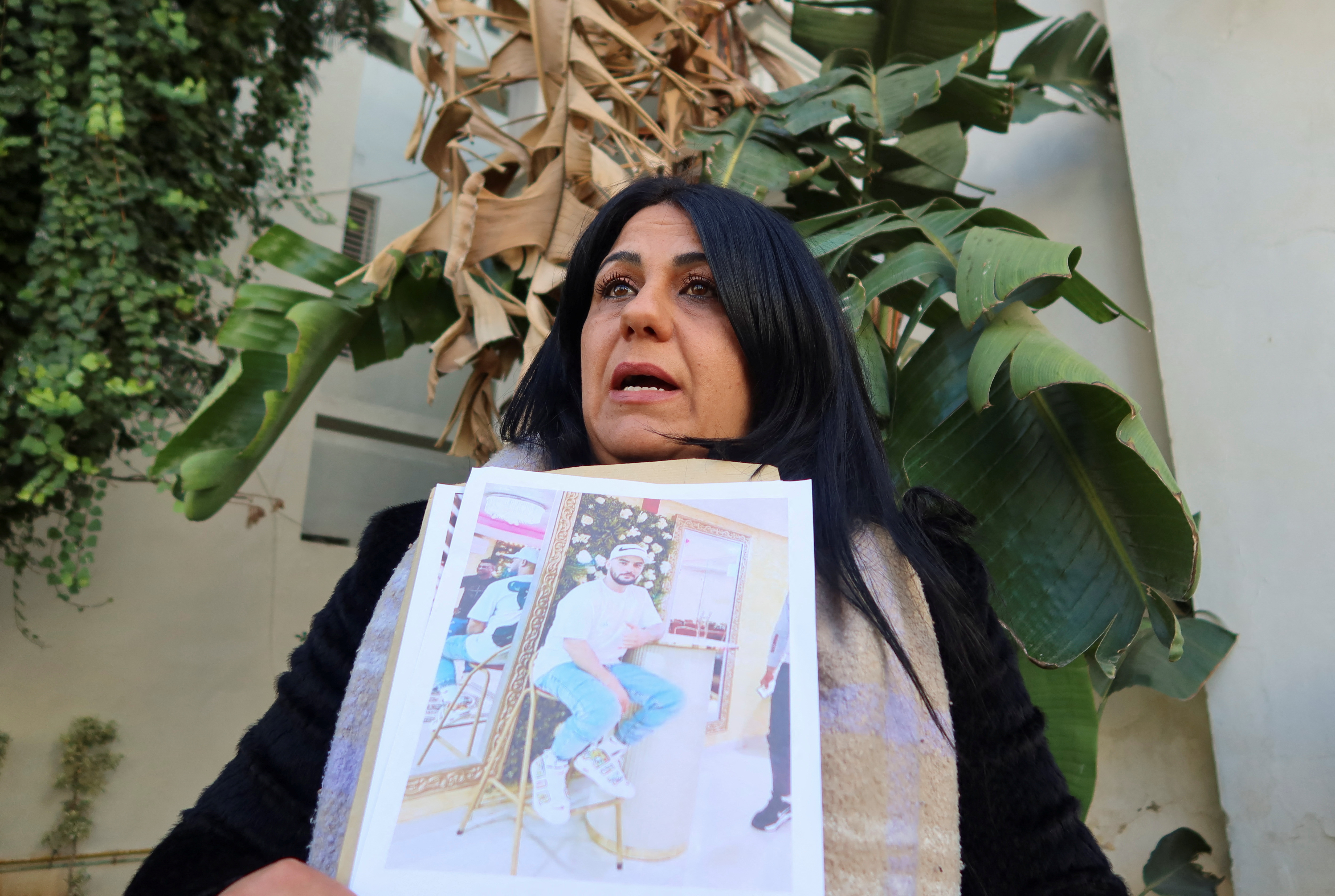 Ines Lafi carries pictures of her brother Mohammed during a protest in Tunis