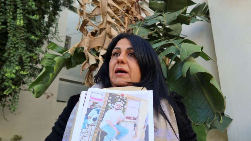 Ines Lafi carries pictures of her brother Mohammed during a protest in Tunis