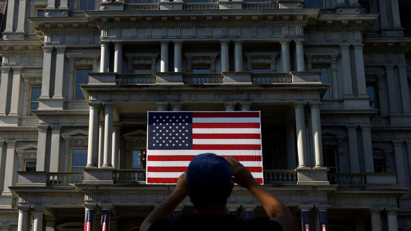 FILE PHOTO: A tourist photographs a U.S. flag on the Eisenhower Executive Office Building