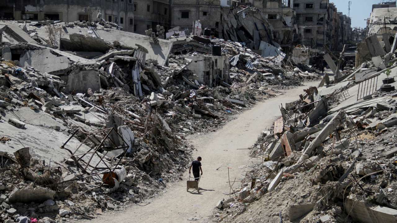 A Palestinian walks among the rubble of damaged buildings, in Beit Lahia