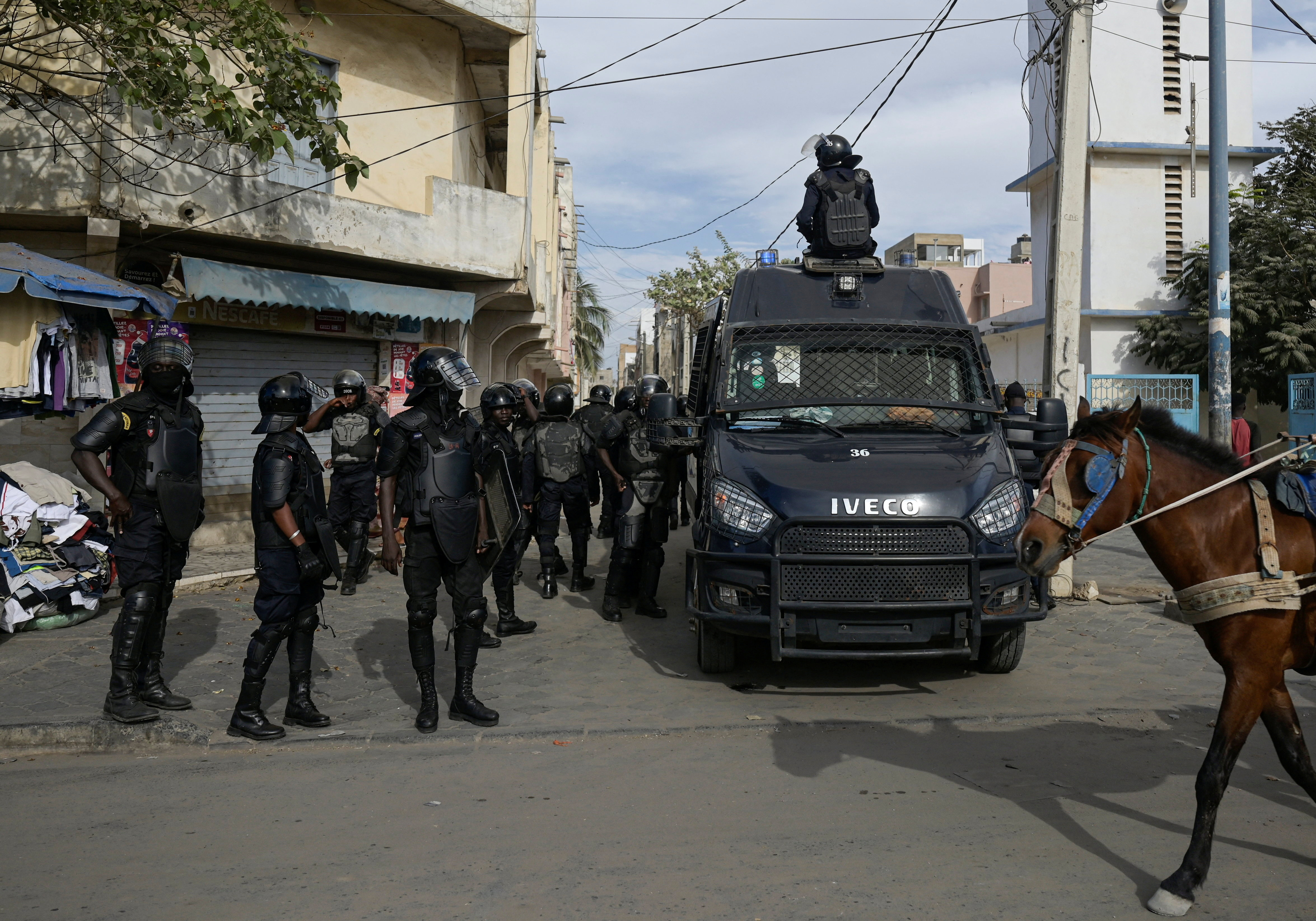Riot police officers stand watch after dispersing a small protest against the postponement of the Feb. 25 presidential election, in Parcelle, district of Dakar