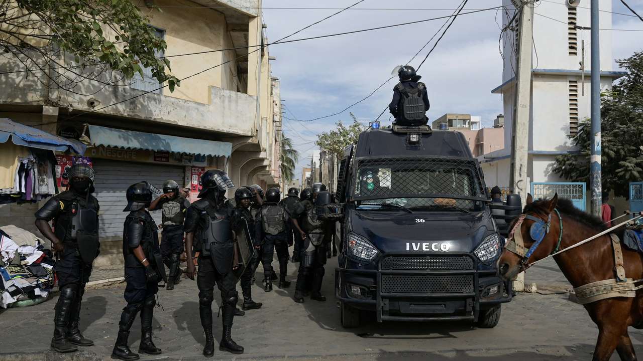 Riot police officers stand watch after dispersing a small protest against the postponement of the Feb. 25 presidential election, in Parcelle, district of Dakar