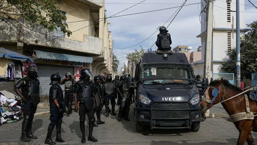 Riot police officers stand watch after dispersing a small protest against the postponement of the Feb. 25 presidential election, in Parcelle, district of Dakar