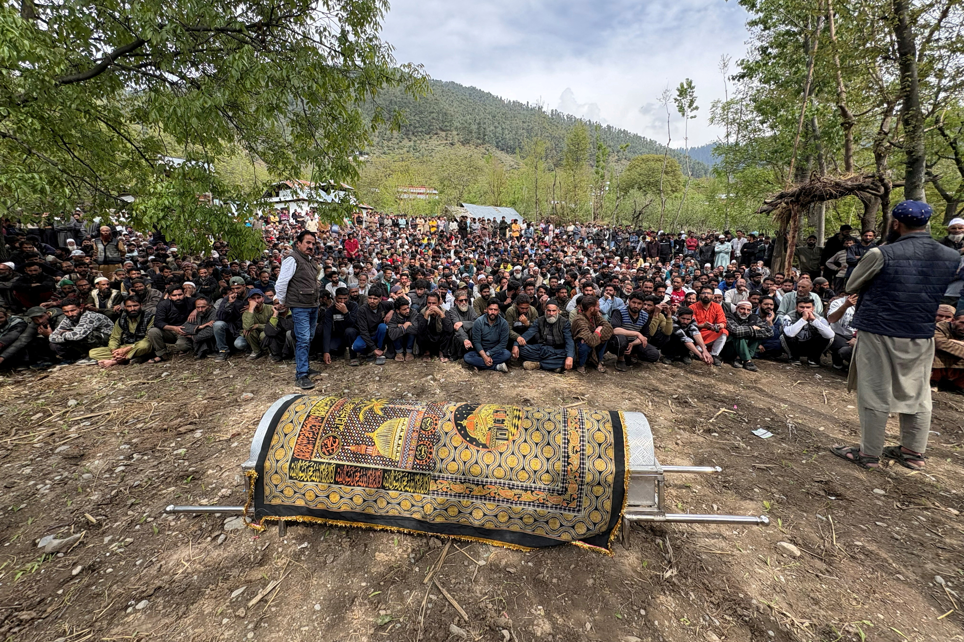 FILE PHOTO: Kashmiri villagers sit next to the coffin of Adil Hussain Shah before his funeral prayers at his village in Hapatnar