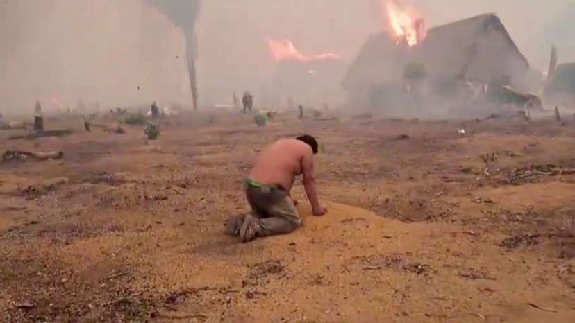 A person kneels as he watches his home being consumed by fire in Riberalta